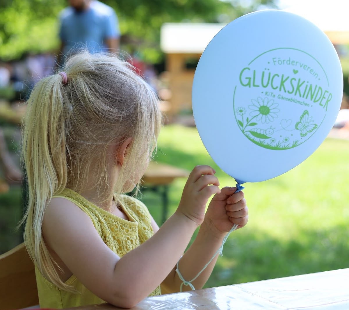 Kind mit einem vollständig sichtbaren Glückskinder-Luftballon
